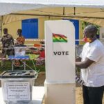 Polling station sign and voters queue in Akwatia for by-election