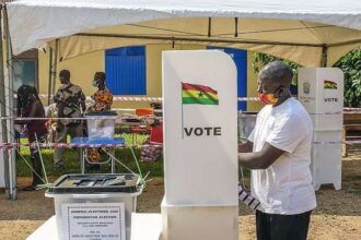 Polling station sign and voters queue in Akwatia for by-election
