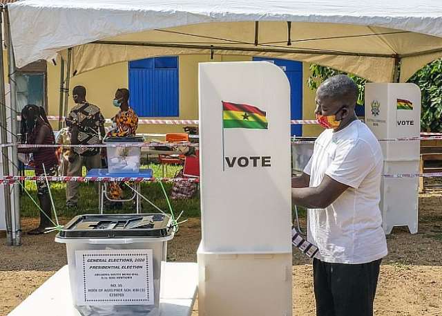 Polling station sign and voters queue in Akwatia for by-election